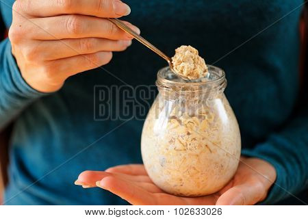 Woman's Slender Hands Holding Glass Jar And Spoon With Overnight Oats Closeup Selective Focus