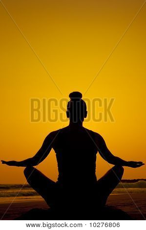 Mujer en pose de yoga junto al océano.