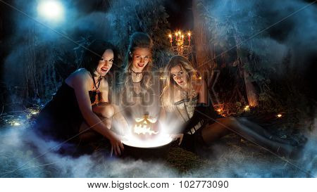 Three Beautiful Witches Are Making Magic. Dark Forest On The Background.