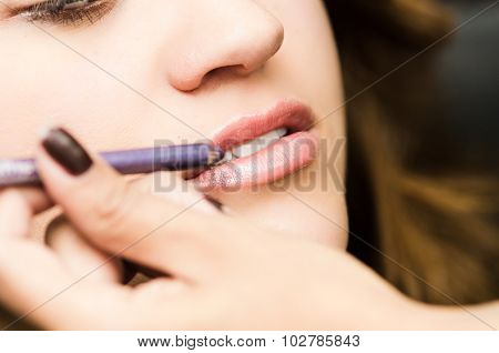 Closeup headshot brunette getting makeup treatment by professional stylist applying lipliner