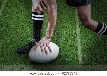 Low section of sportsman holding rugby ball against pitch with lines