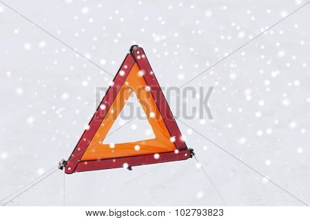 transportation and winter concept - closeup of warning triangle on snow