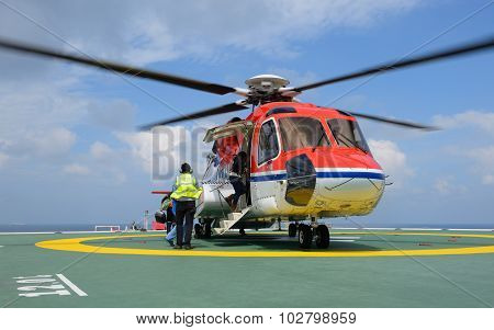 The officer take care passenger to embark helicopter at oil rig platform