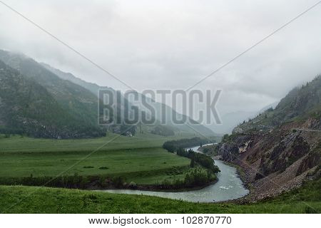 River In Valley Between The Mountains On Mist Fog  Rainy Weather