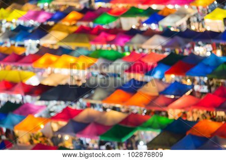Close up aerial view of multiple colour roof top weekend market, abstract blurred bokeh light backgr