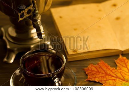 Tea Still Life With Samovar, Maple Leaves, On Wooden Background. Empty Open An Old Vintage Book. Rus