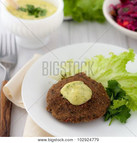 bean burger without a bun served on a plate with aioli sauce