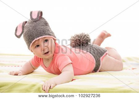 Little baby girl in croched bunny costume laying and looking away
