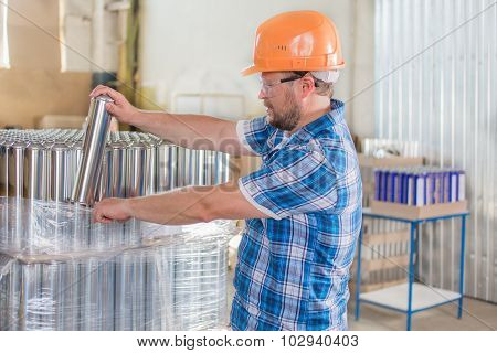 Worker in helmet storage with tin blank tubes