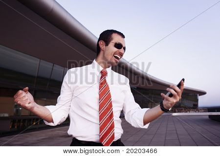 흰 셔츠와 선글라스에 좋은 뉴스를 받은 데로 응원에 성공적인 행복 한 사업가 