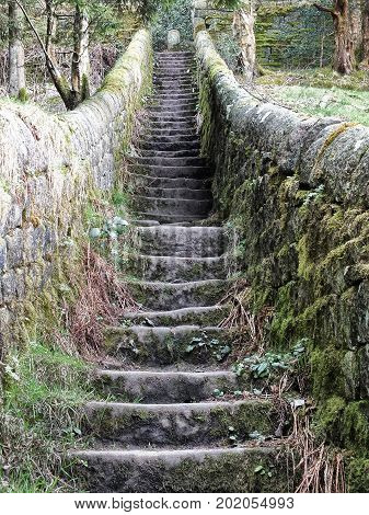 steep stone stairs with walls joining countryside pathways with grass and trees