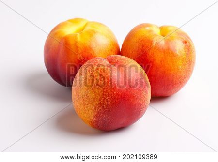 Three Nectarines sitting on a White Background