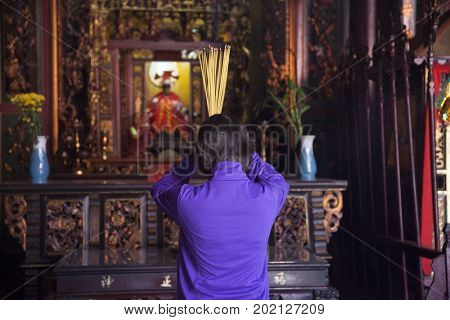 Ho Chi Minh City, Vietnam - March 26, 2017: Woman praying in Ong Bon Pagoda, dedicated to Ong Bon, the guardian who presides over happiness and wealth, in Cholon, the Chinatown area of Saigon