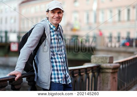 Mature tourist with backpack on the embankment of Griboyedov canal in St. Petersburg, Russia