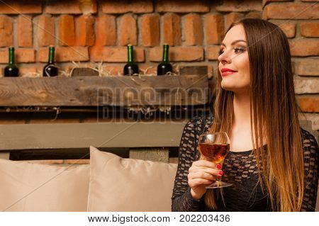 Elegant beauty lady long hair full make up wearing black dress tasting wine in rural cottage interior celler
