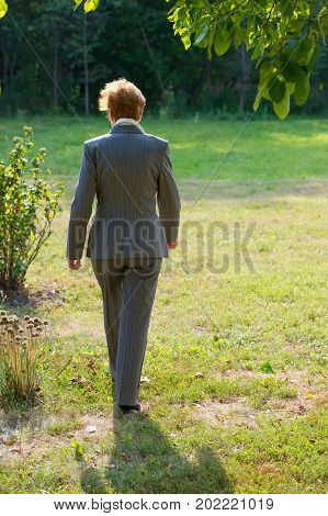 business woman of an age is walking in the park. Age eighty years. A woman in a business suit.