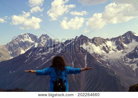 Young woman with arms outstretched in the mountains. The concept of happiness, freedom, pleasure