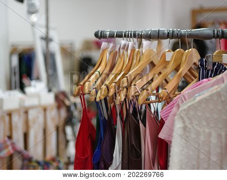 A big assortment colorful clothes for women on a shop background. Various fashionable color shirts and dresses in a expensive boutique. Luxury and stylish garment on hangers. Fashion concept.