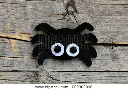 Creating a felt Halloween spider ornament. Step. Cute Halloween spider ornament isolated on a vintage wooden background. Things to make with felt sheets. Top view. Closeup