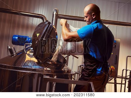 Brewer in brewhouse pouring out the malt to the tank