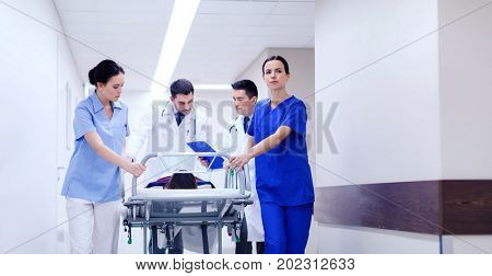 profession, people, health care, reanimation and medicine concept - group of medics or doctors carrying unconscious woman patient on hospital gurney to emergency