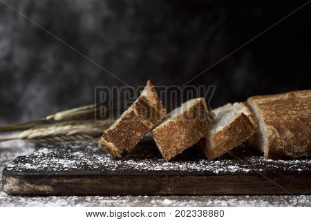 closeup of a loaf and some slices of pa de vidre or pa de coca, a bread typical of Catalonia, Spain, on a rustic wooden table