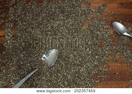 Chia seeds with spoons on wooden background.Today, chia is increasingly known as a great source of concentrated omega-3 fats and fiber.