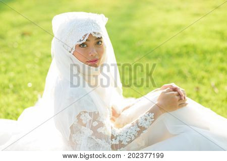 Portrait of a beautiful muslim bride with make up in white wedding dress with beautiful white headdress natural light.