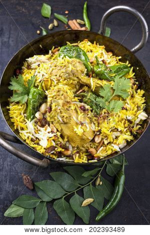 Indian chicken biryani with nuts and raisins as close-up in a korai 