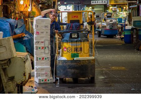 TOKYO, JAPAN JUNE 28 - 2017: Unidentified man with a small cargo yellow machine, inside of a Fish Market Tsukiji in Tokyo Japan, Tsukiji Market is the biggest wholesale fish and seafood market in the world.