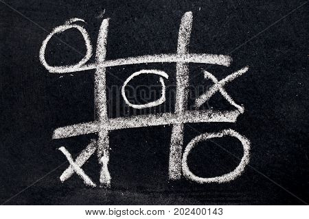 White chalk drawing as Tic Tac Toe with the winner and loser shape on black board background