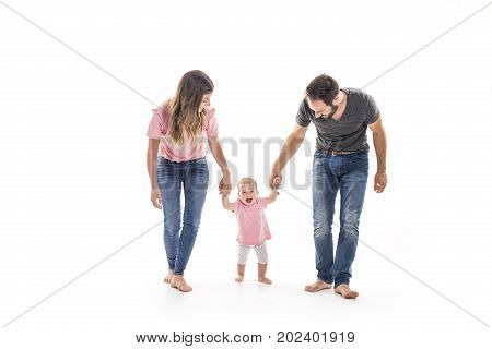 A Couple of young parents helping their baby to make first steps on floor in their home