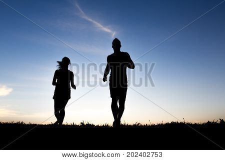 A silhouette of a jogger couple in sunrise