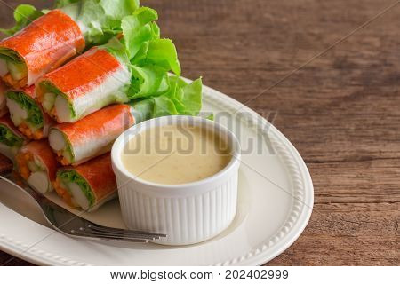 Fresh spring rolls with fresh vegetable and crab stick served with spicy salad cream dipping sauce. Rolls salad or fresh spring roll on white plate healthy delicious food for appetizer or meal. Fresh spring rolls in fusion food style.