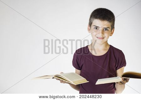 Portrait happy smiling boy holding two open books. Teenager smiling and looking at camera. Cheerful child holding books. The concept of back to school.