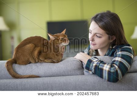 A girl watching tv with cat in the living room