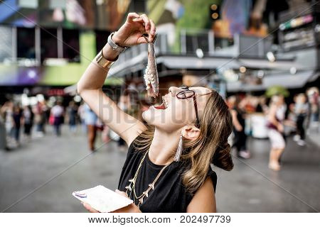 Young woman eating herring with onions traditional dutch snack in Rotterdam market