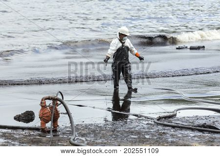 RAYONG THAILAND - JULY 31 2013: A worker in biohazard suit during the clean-up operation from crude oil spilled into Ao Prao Beach on July 31 2013 in Rayong province Thailand.