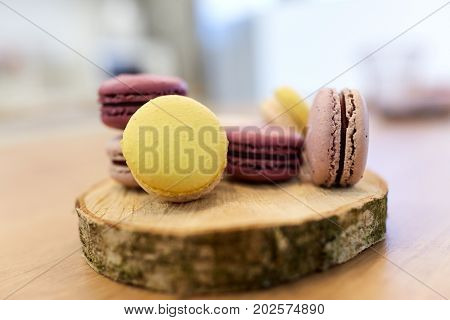 cooking, confectionery and baking concept - different macarons on wooden stand