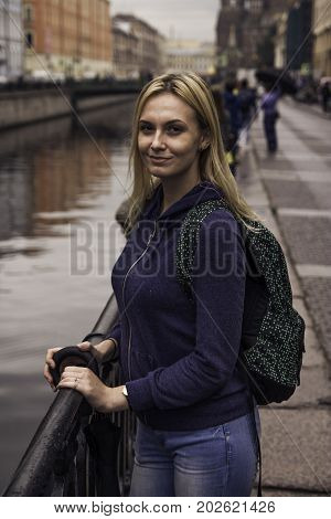 Beautiful Girl In A Jacket Looks At The Camera Leaning On A Handrail In St. Petersburg
