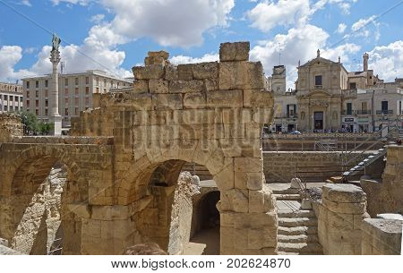 LECCE ITALY - JULY 27 2017: the Ancient Roman amphitheater and the Piazza San Oronzo with is monumental column in the background