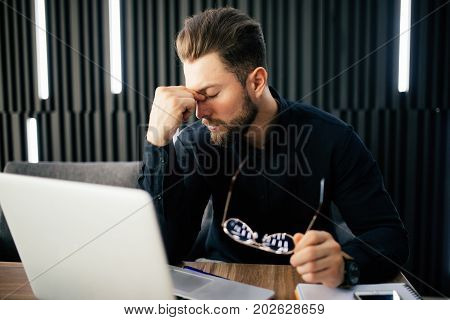 Exhausted Tired Businessman Working On Laptop At Office, Massaging Nose Bridge, Holding Glasses, Fee