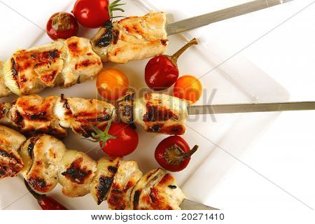 Chicken shish kebab på hvidt fad med grøntsager