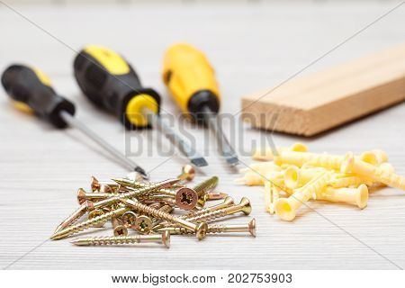 Screwdrivers, Wooden Block And Screws On White Wooden Background