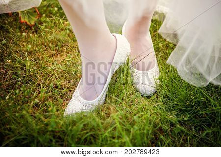 the bride wears white shoes on foot in the wedding day. close-up shoot