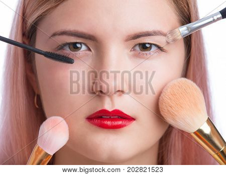 Beautiful young woman with makeup brushes around face