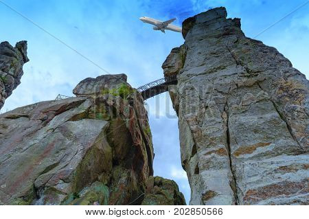 The external stones marked sandstone rock formation in the Teutoburg Forest Germany North Rhine Westphalia. In the background in the sky a commercial aircraft.