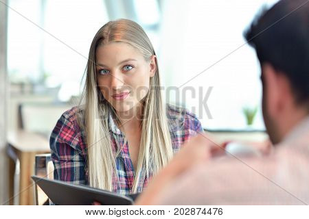 Young couple - man and woman - drinking coffee in a cafe in front of a glass facade.