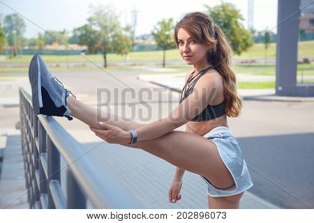 Long Haired Sporty Girl In A Stylish Silver Colored Shorts And Dark Green T-shirt Is Exercising On A