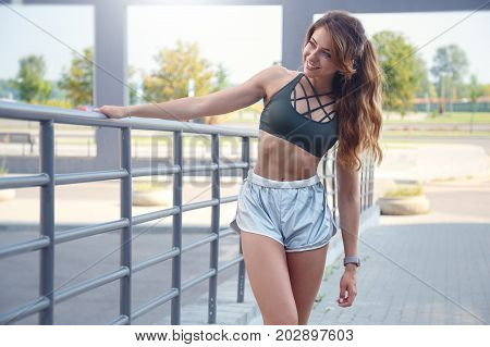 Long Haired Sporty Girl In A Stylish Silver Colored Shorts And Dark Green T-shirt Is Exercising On A